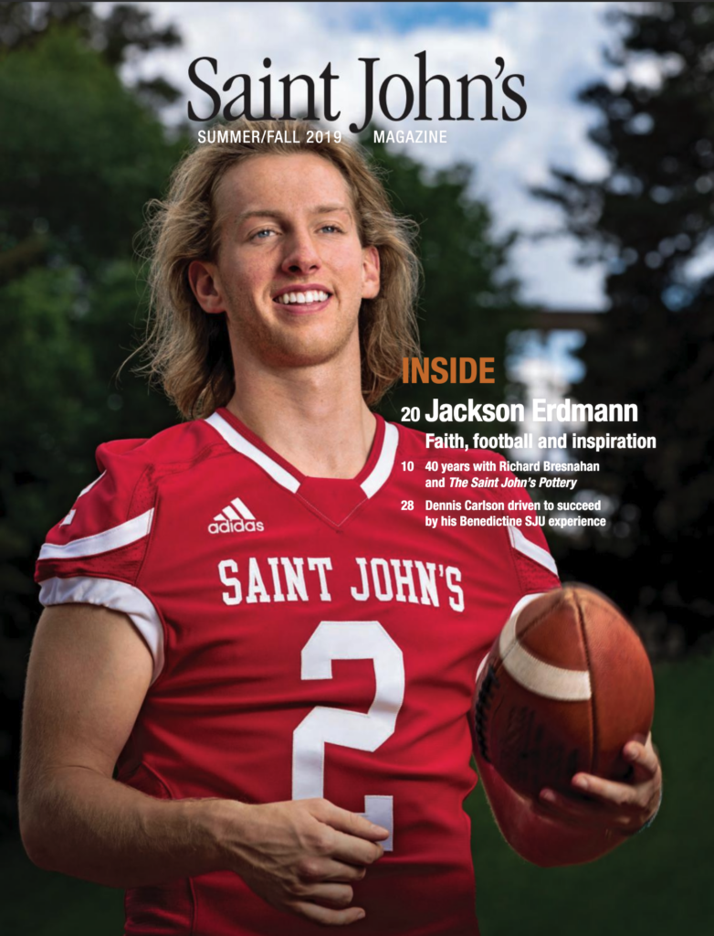 A football player wearing a red jersey with the number 2 holds a football with both hands in front of a blurred outdoor background. The magazine cover reads "Saint John's - Summer/Fall 2019.